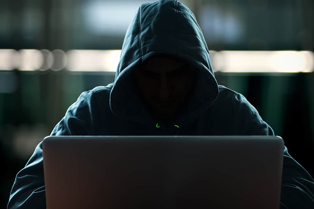a person wearing a hoodie using laptop